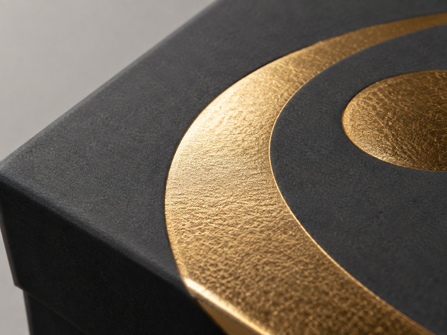 Close-up of a foil-stamped detail catching the light on a matte packaging lid